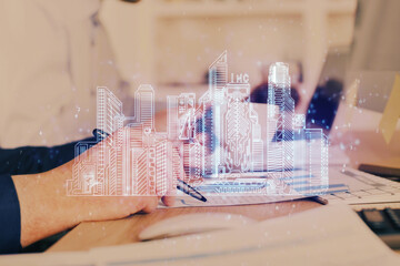 Abstract holographic city on man's hand writing notes background. Multi exposure.