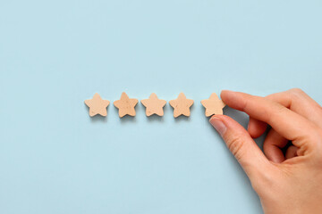 A person puts five wooden stars in a row. Symbolic image of the rating statement