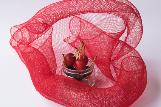 Cherry On A Red Mesh Background