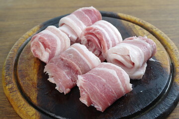 raw bacon with parsley on white plate