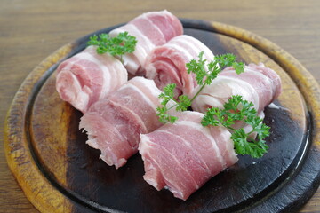 raw bacon with parsley on white plate
