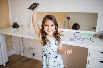 Fototapeta na wymiar Little girl in front of a desk lifting an American passport high above her head