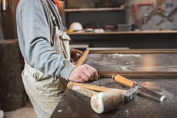 Male carpenter working on old wood in a retro vintage workshop.