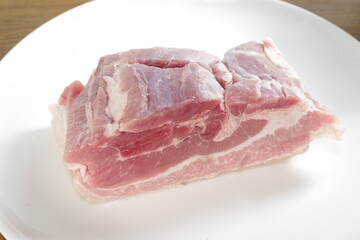raw bacon with parsley on white plate