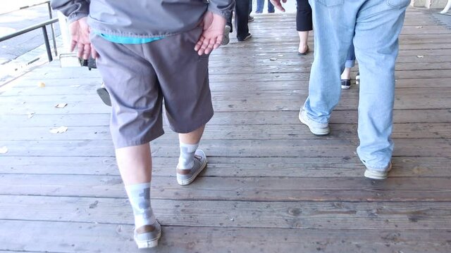 Crowd of older people walking on a wooden walkway.