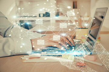 Envelop hologram drawing with businessman working on computer on background. Electronic mail concept. Double exposure.