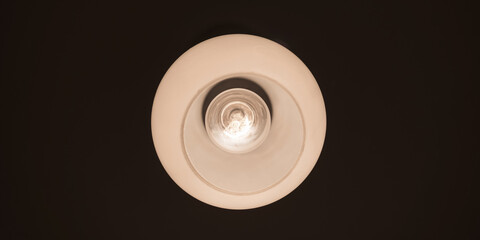 light from bulb hanging on dark ceiling of home apartment