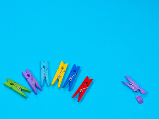 Spring-type wooden clothespins deride or laugh fracture leg on blue background. Bullying,...