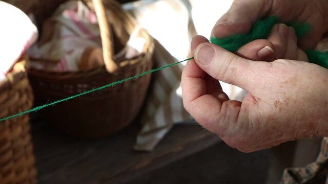 Forming green dyed sheeps wool into home made yarn by hand.