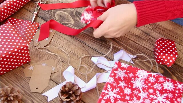 Woman ties a ribbon bow and wrapping presents