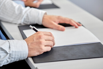 people, business and corporate concept - close up of businessman with pen and paper at office