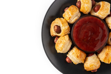 Pigs in blankets. Mini sausages wrapped in puff pastry with ketchup sauce isolated on white background