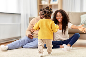 family, parenthood and people concept - happy african american mother and father playing with baby daughter at home