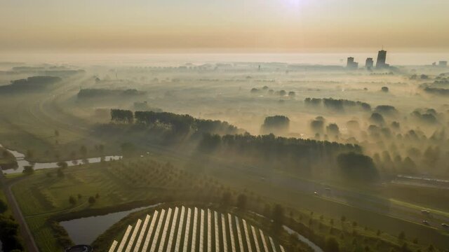 Solar panel island in in a suburban neighbourhood in The Netherelands during golden sunrise on a foggy morning, aerial view, timelapse