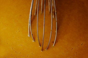 closeup photo of whisk rods beating dough