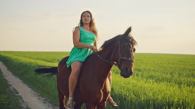 A woman is riding a horse at sunset.