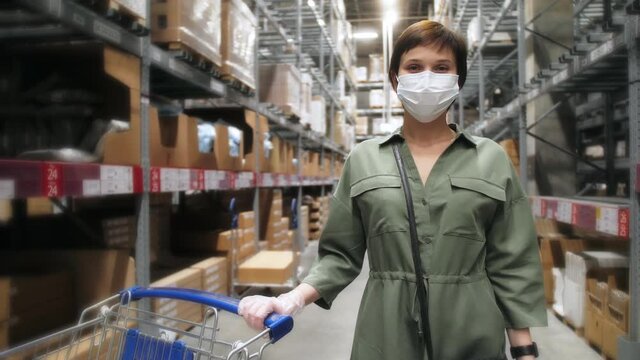 Attractive woman customer wearing protective face mask and gloves standing in shopping mall during pandemic. Buyer walking