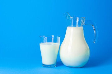 Glass jar with fresh milk against blue background