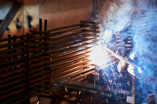 A person works with welding, sparks, close up, construction