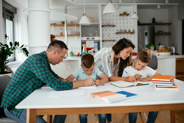 Parents helping the kids with their homework. Litlle boys learning at home.