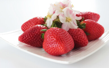Intensive red strawberries on a white plate.