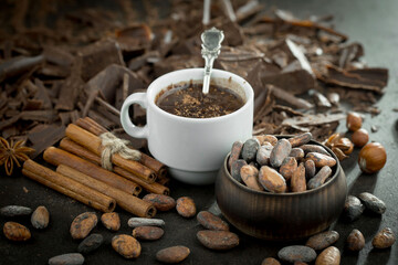 Hot chocolate on an old background in a composition with cocoa beans and nuts.
