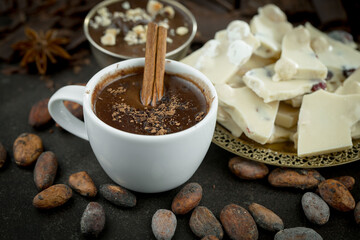 Hot chocolate on an old background in a composition with cocoa beans and nuts.