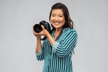 photography, profession and people and concept - happy smiling asian female photographer with...