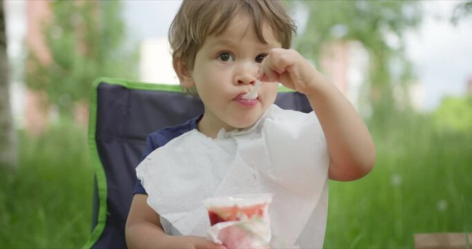 Litte girl eating ice cream with spoon in the park.