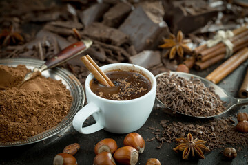 Hot chocolate on an old background in a composition with cocoa beans and nuts.