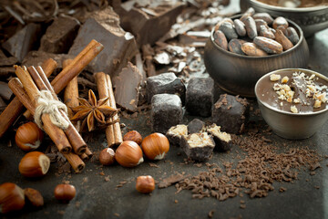Dark chocolate in a composition with cocoa beans and nuts, on an old background.