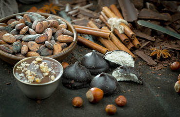 Dark chocolate in a composition with cocoa beans and nuts, on an old background.