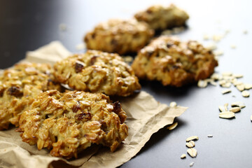 Homemade oatmeal cookies with raisins on craft paper on a black background
