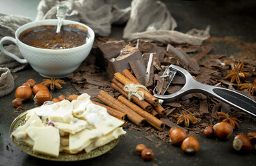 White and black chocolate on the table in a composition with nuts and cocoa beans.