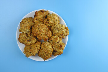 A stack of homemade oatmeal cookies with raisins on a blue background