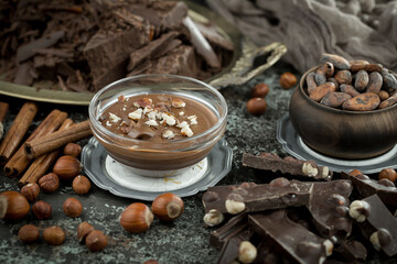 Hot chocolate on an old background in a composition with cocoa beans and nuts.
