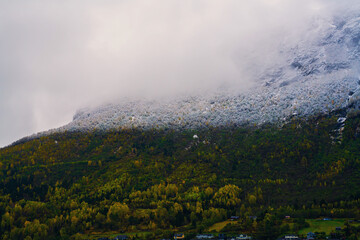 Mountain ridge with a clear snow line covered in dense stormy clouds.