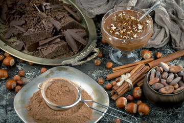 Dark chocolate in a composition with cocoa beans and nuts, on an old background.