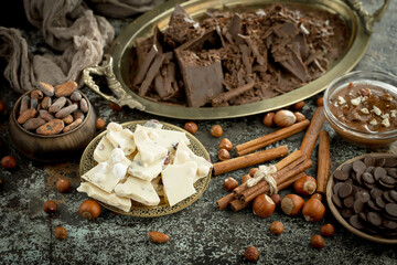 Dark chocolate in a composition with cocoa beans and nuts, on an old background.