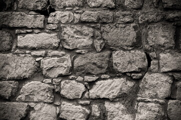 Texture of an old wall with different size stones. 
Black and white vintage ancient stacked stone wall texture, masonry background.