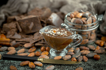 Hot chocolate on an old background in a composition with cocoa beans and nuts.