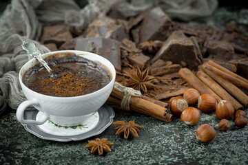 Hot chocolate on an old background in a composition with cocoa beans and nuts.