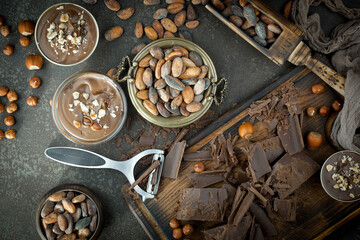 Dark chocolate in a composition with cocoa beans and nuts, on an old background.