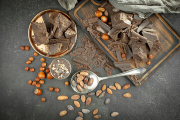 Pieces of dark chocolate and cocoa beans in composition on old background