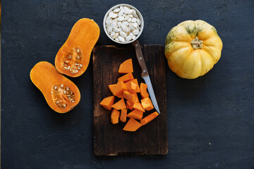 Cut pieces of raw pumpkin on wooden board on table
