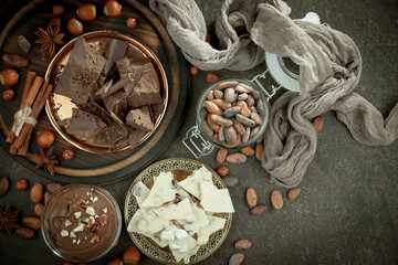 Pieces of dark chocolate and cocoa beans in composition on old background