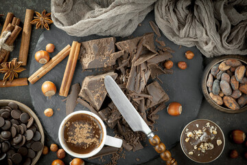 Pieces of dark chocolate and cocoa beans in composition on old background