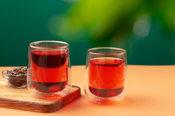 Two glass cups of black tea on beige table