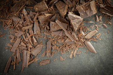 Pieces of dark chocolate and cocoa beans in composition on old background