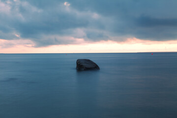 Fototapeta na wymiar Sunset over the sea. Stones on the foreground